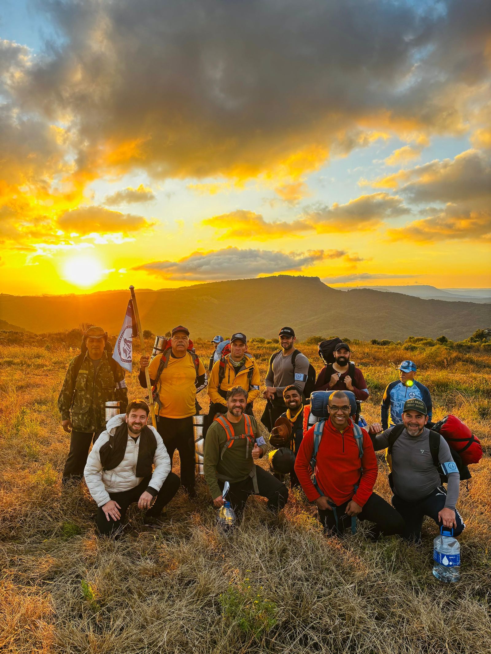 Grupo de participantes reunidos no campo ao pôr do sol